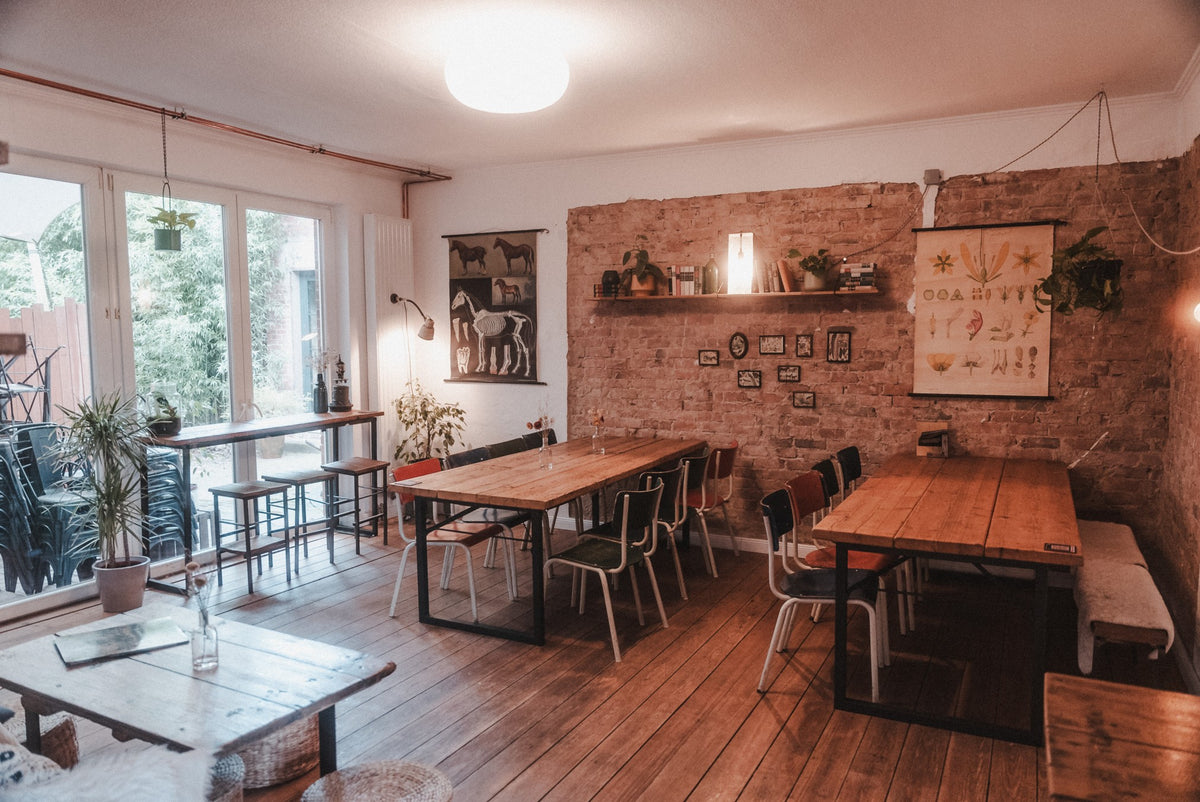 Heller Gastraum mit Backsteinwand und Holztischen im Café