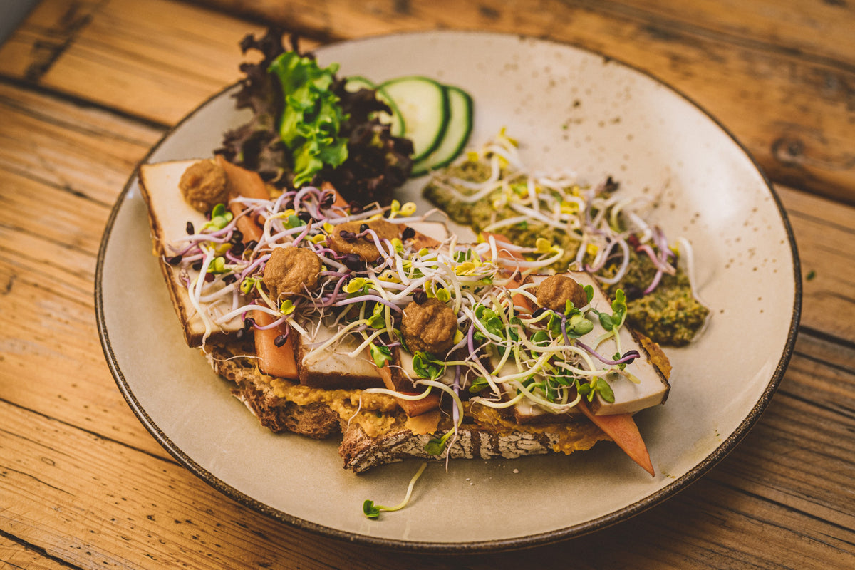 Belegtes Brot mit Sprossen und Gemüse auf dem Teller