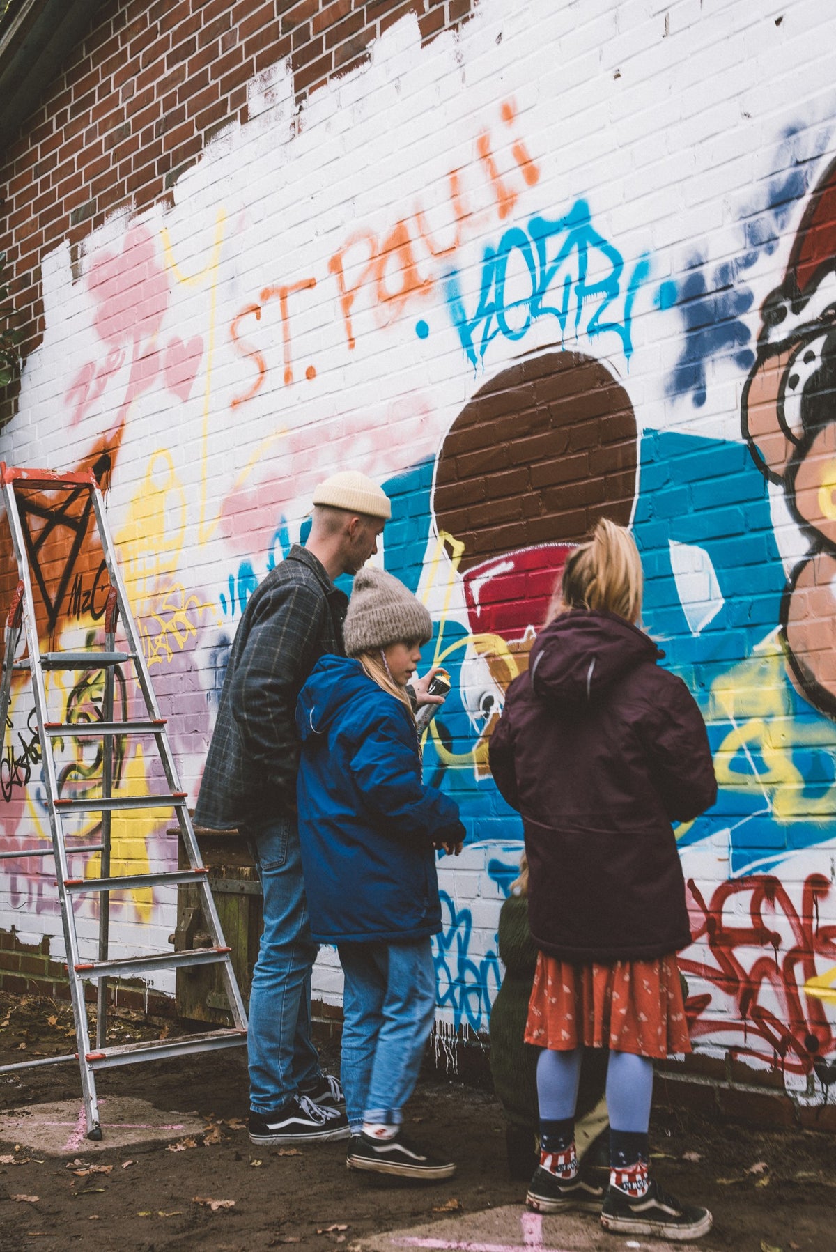 Kinder und Erwachsene sprühen an der Graffitiwand