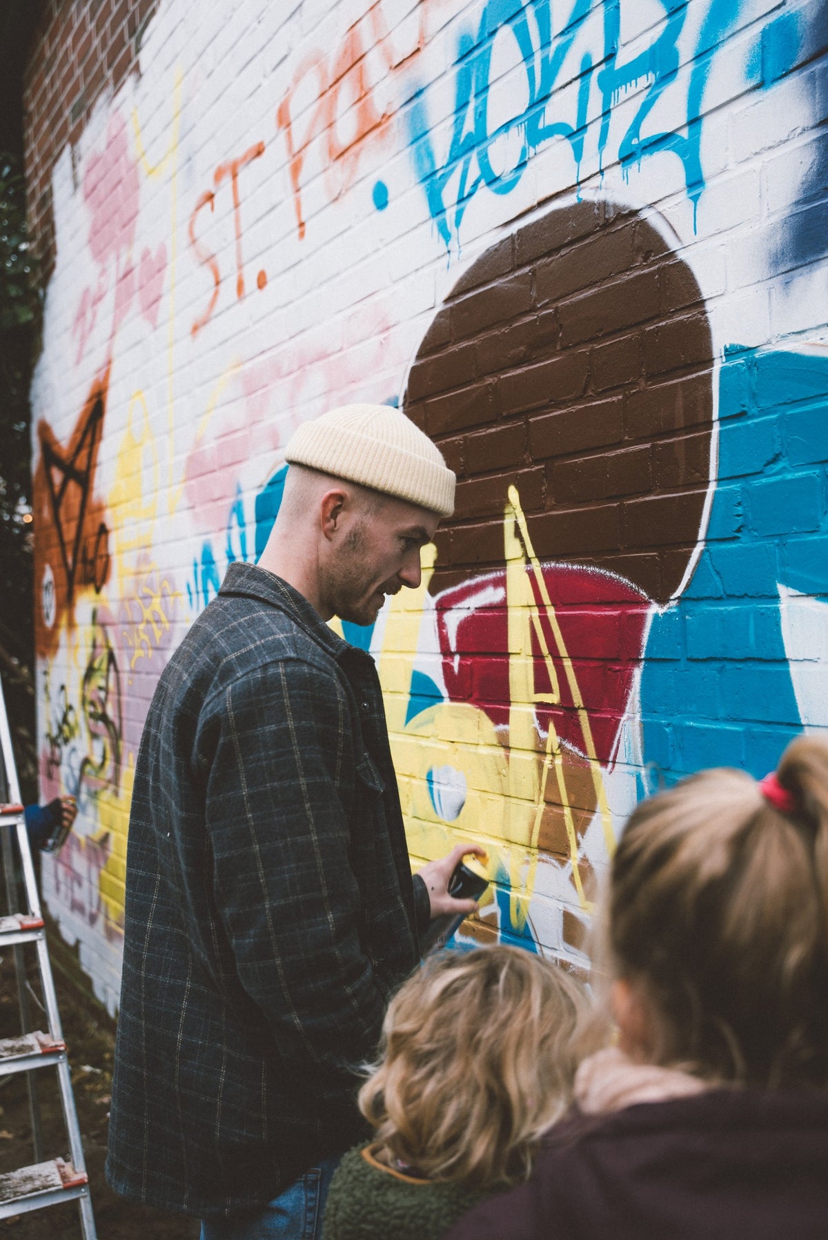 Vater mit Kind sprüht an der Graffitiwand