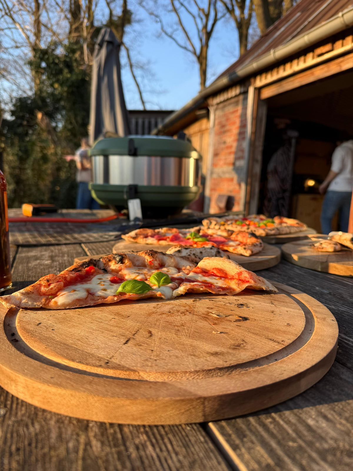 Pizzen auf Holzbrettern draußen am Pizzaofen im Kliemannsland