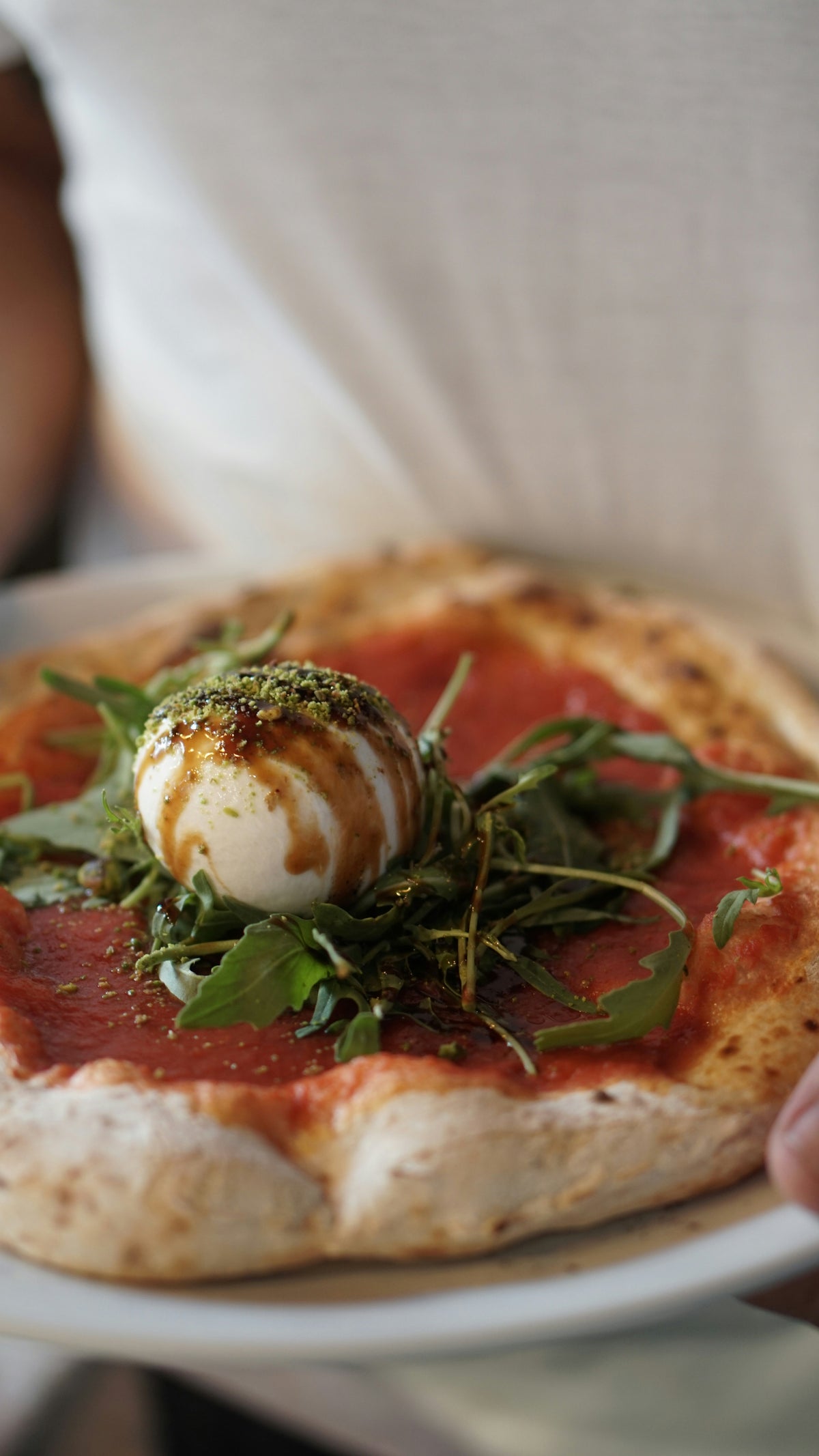 Pizza mit Burrata und Rucola auf dem Teller
