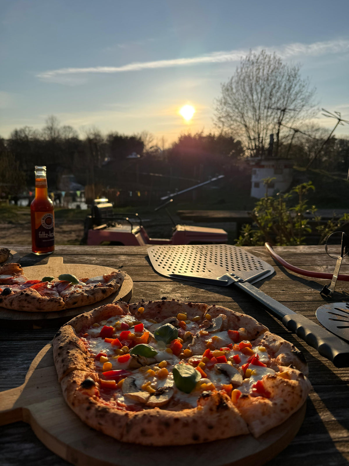 Pizza auf dem Holzbrett bei Sonnenuntergang auf dem Hof
