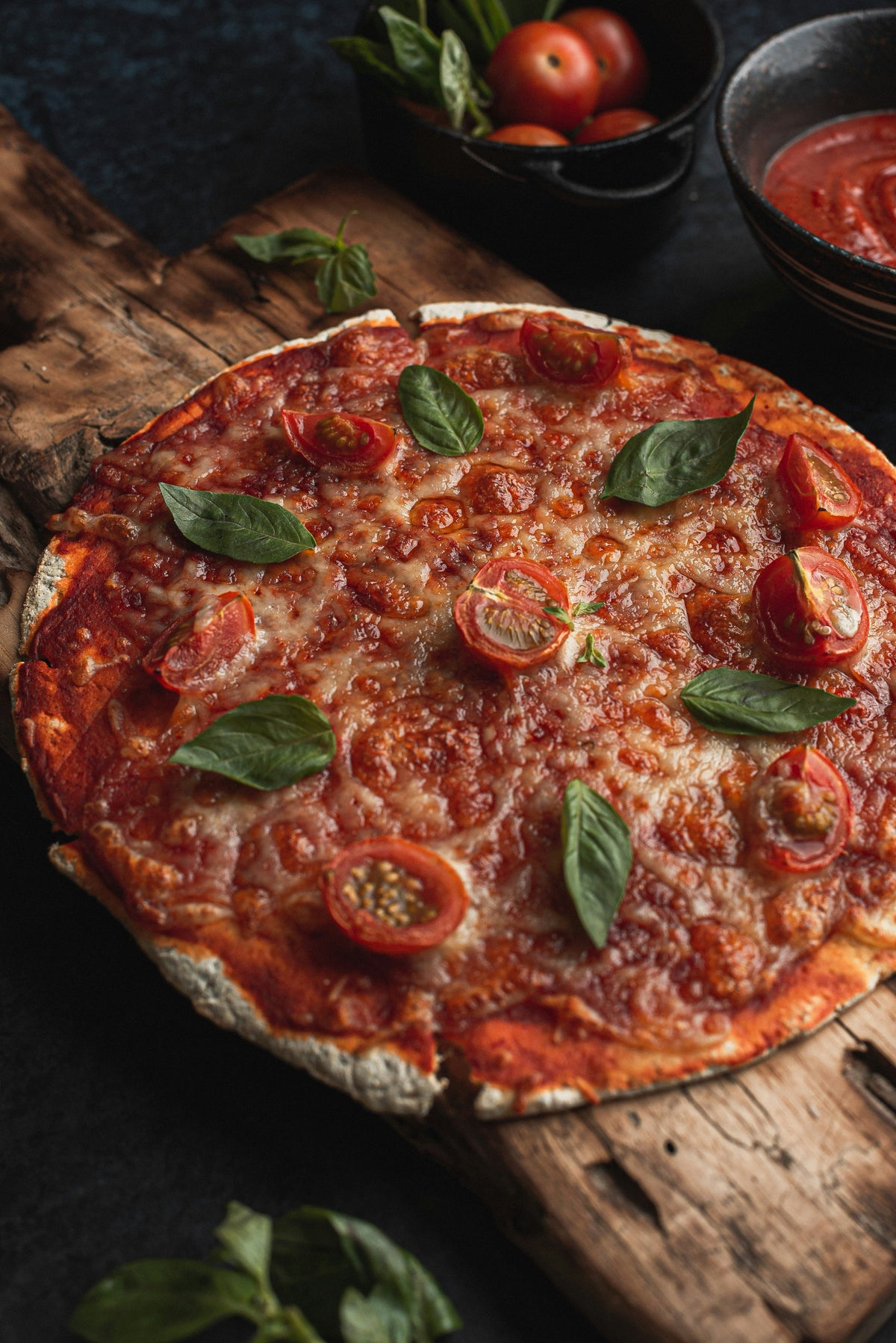 Pizza mit Tomaten und Basilikum auf einem Holzbrett