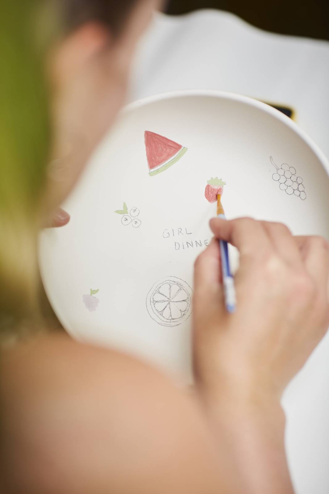Frau bemalt einen Teller mit kleinen Motiven