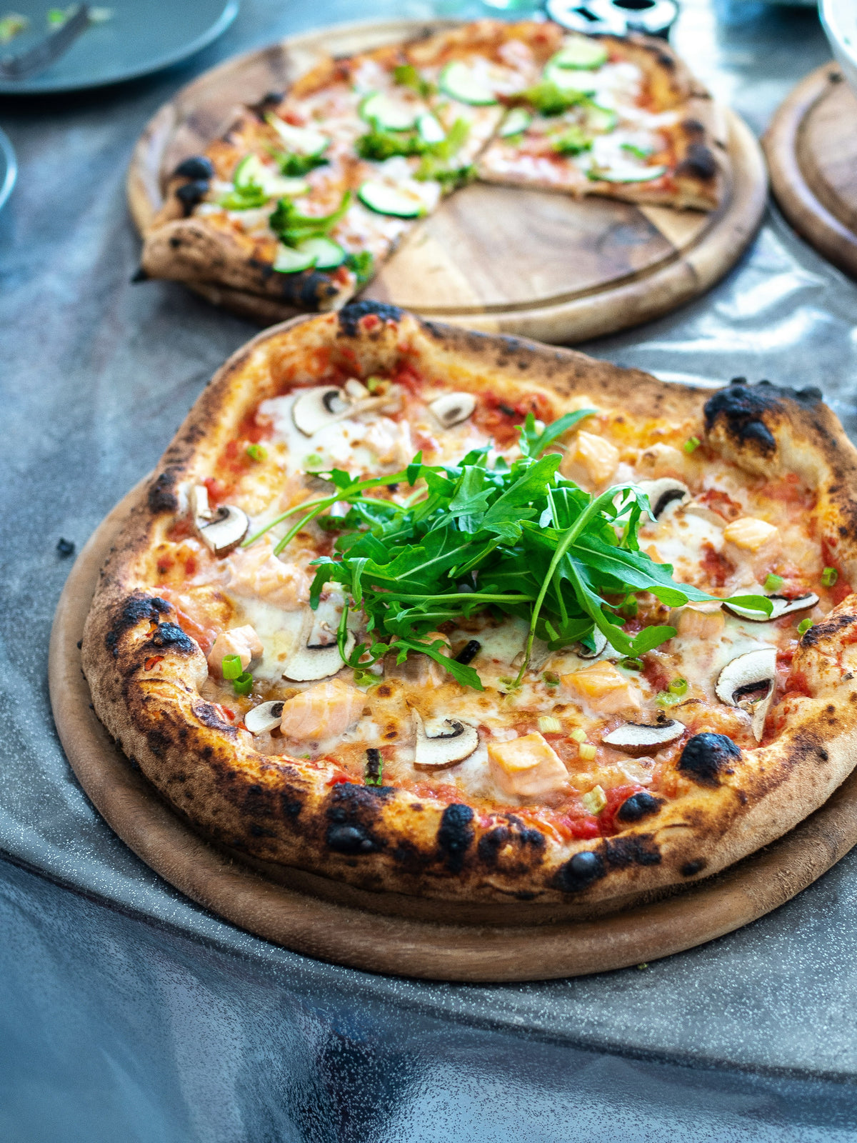 Pizzen mit Pilzen und Rucola auf Holzbrettern